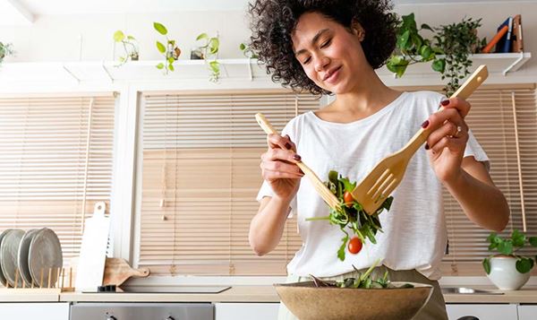 Happy young women in the kitchen making a fresh salad.