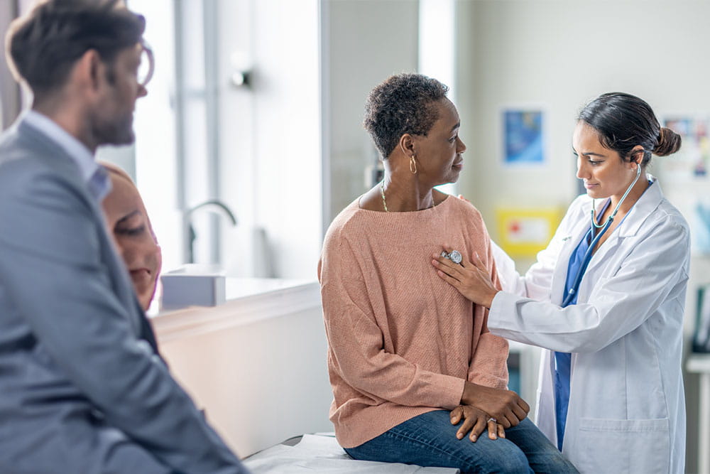 Doctor listening to female patient heartbeat with stethoscope picture