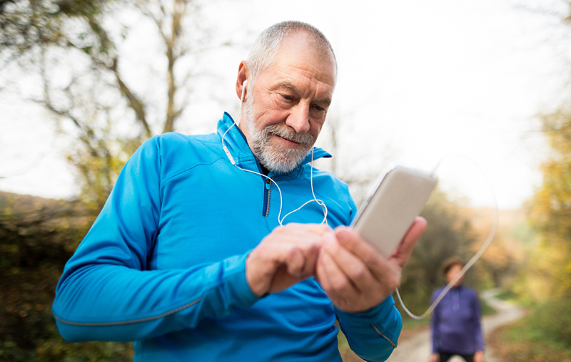 senior runner using headphones choosing song