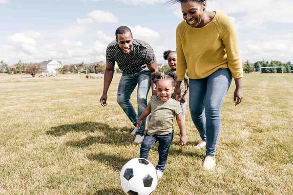 mom and dad playing soccer with two young daughters