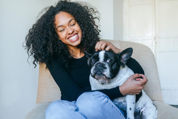 Young happy woman sitting in a chair with her dog.